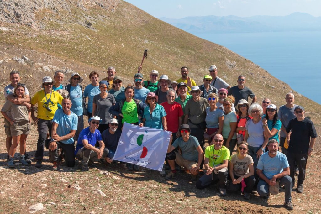 Foto di gruppo degli escursionisti su un pendio con il mare sullo sfondo