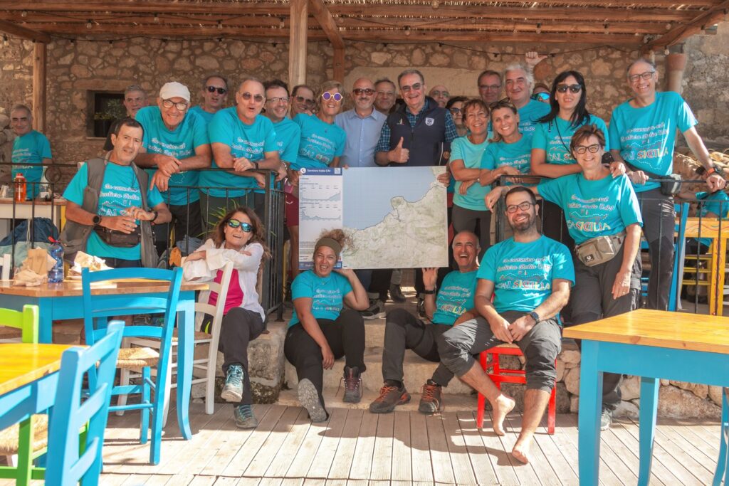 Partecipanti al trekking riuniti con uno striscione alla Grotta Mangiapane